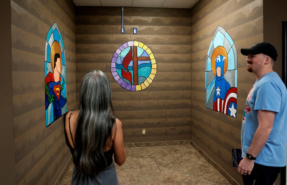 Esther Carey, left, and Noah Gerber look at paintings of stained glass on the wall during the grand opening for Sanctuary Comics &amp; Games in Oklahoma City, Thursday, Aug. 1, 2024.